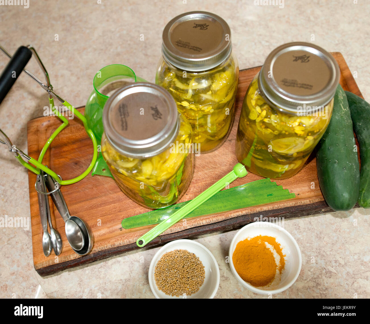 Pickles in Jars sitting on a Cutting Board on a Kitchen Counter along
