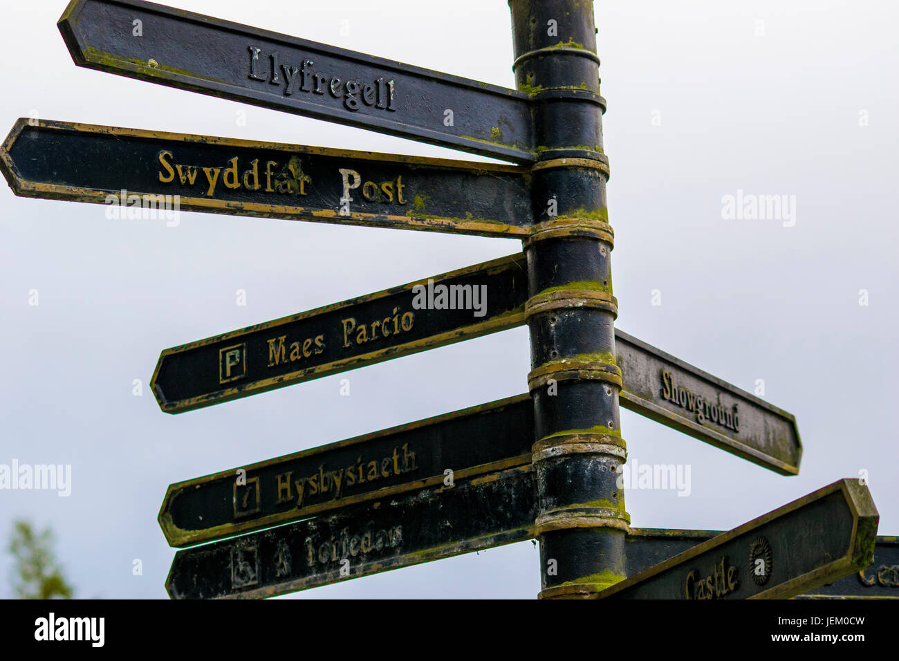 Village sign post written in the Welsh language in Builth Wells displaying directions for people. Stock Photo