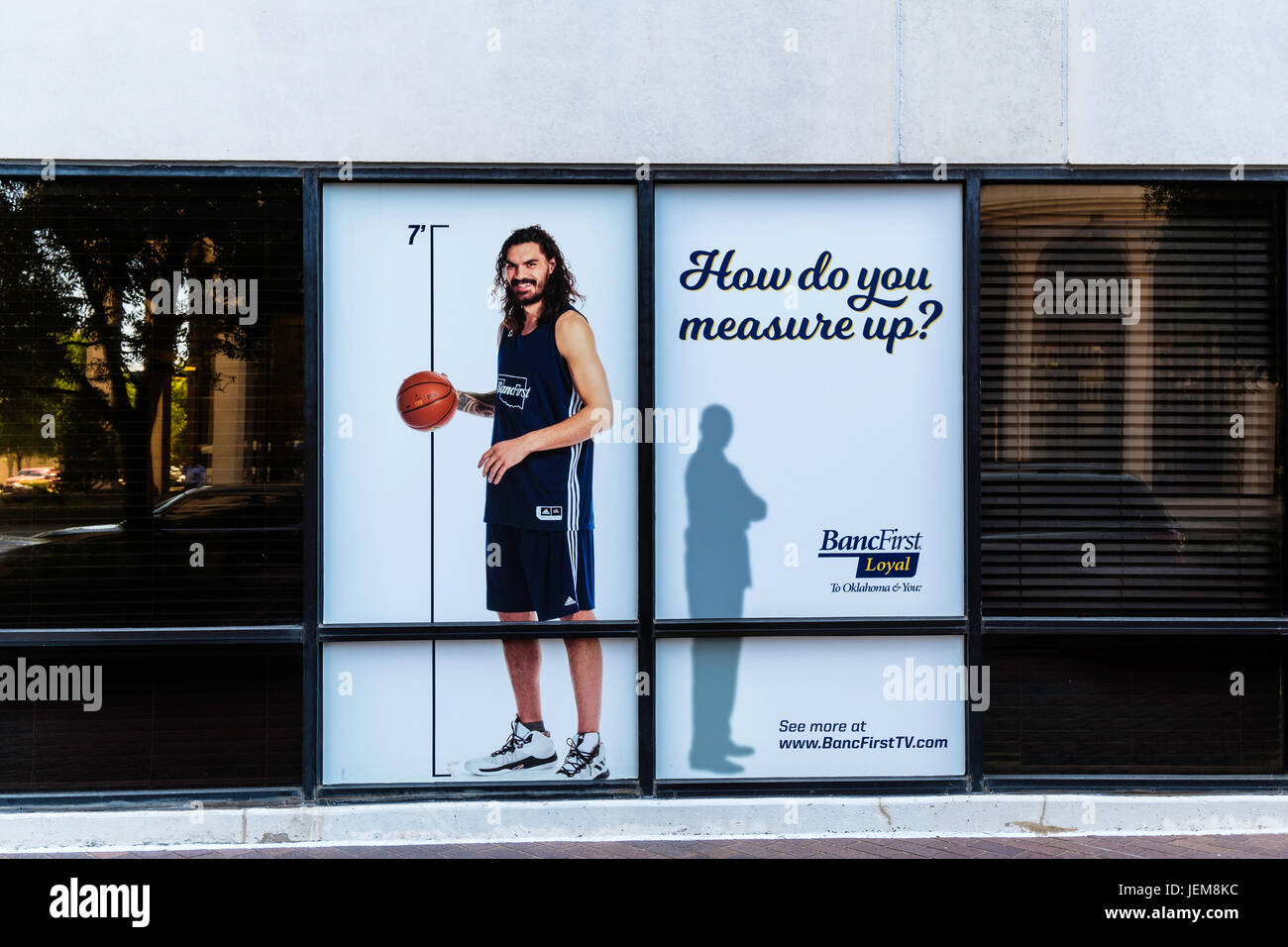 A life sized poster of NBA player Steven Adams in the window of BancFirst in downtown Oklahoma City, Oklahoma, USA. Stock Photo