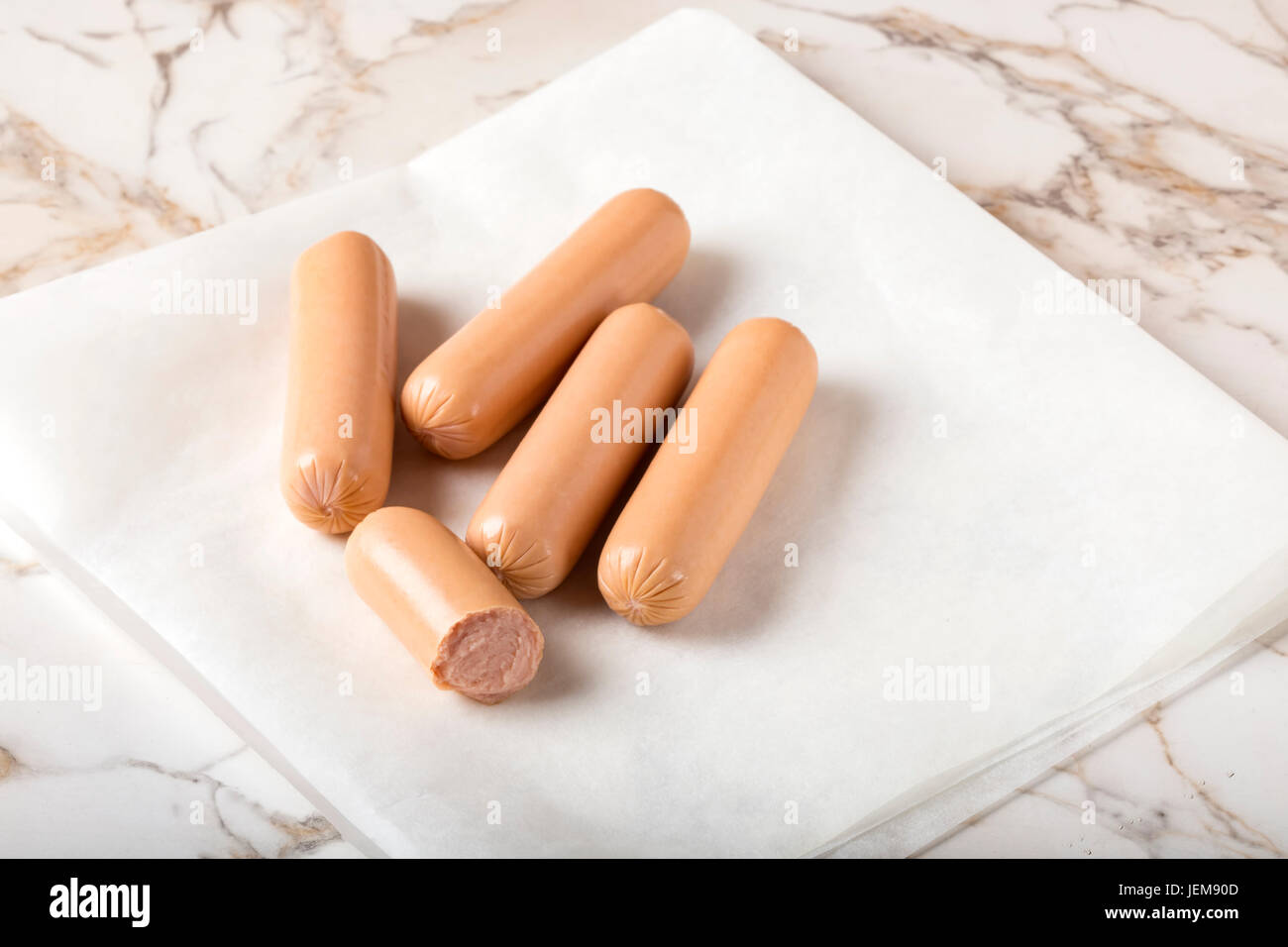 Sausages (Frankfurter) on rustic table with paper (close-up shot) Stock Photo