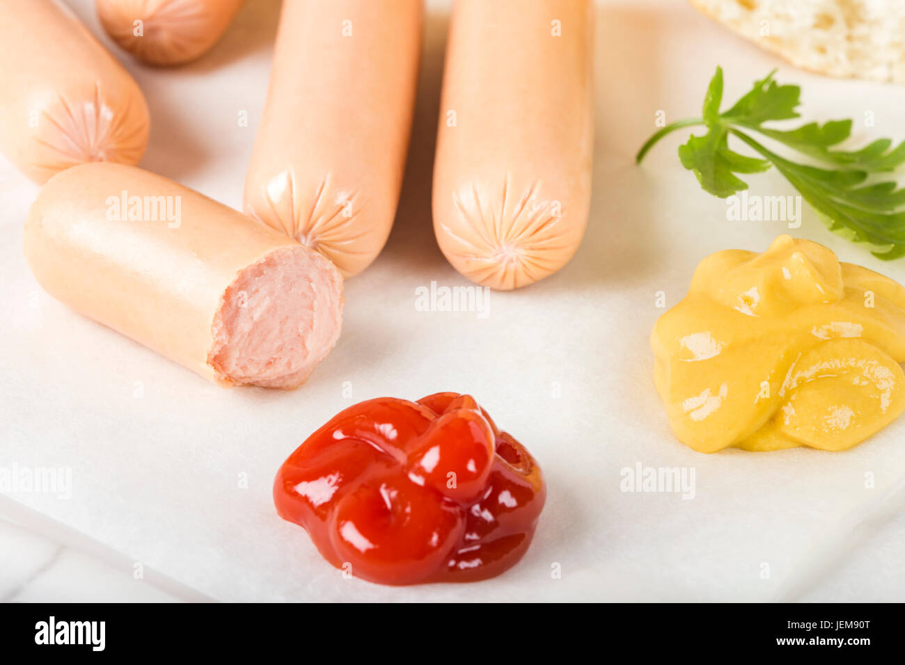 Sausages (Frankfurter) on paper with bread, mustard and ketchup Stock Photo