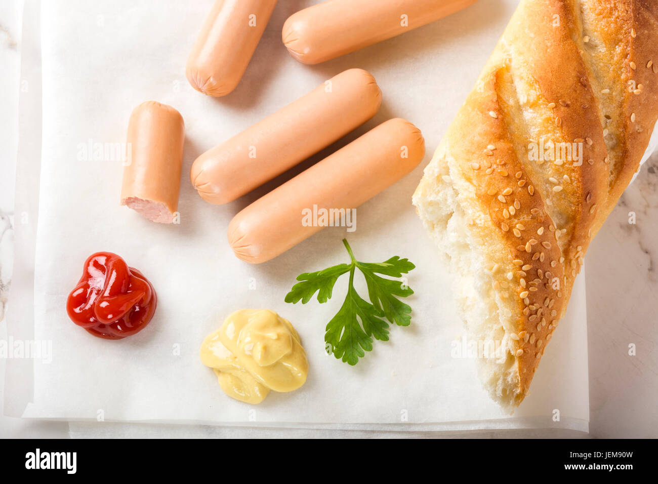 Sausages (Frankfurter) on paper with bread, mustard and ketchup Stock Photo