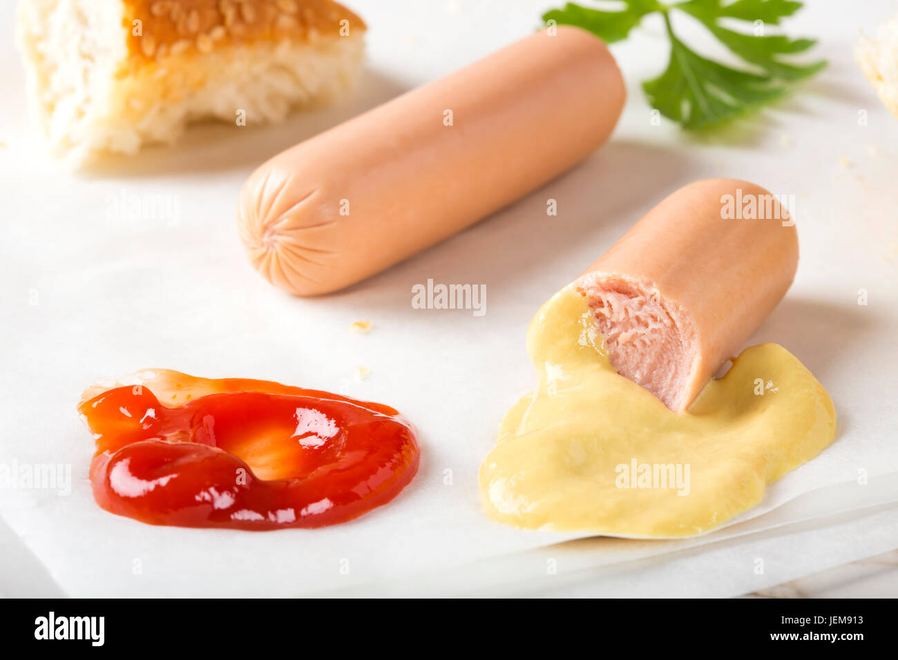 Eating Sausages (Frankfurter) on paper with bread, mustard and ketchup Stock Photo