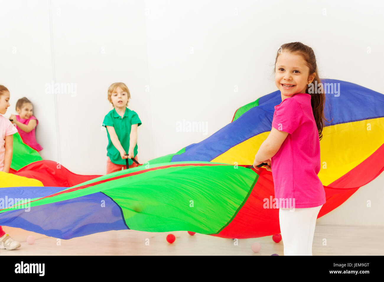 Happy girl playing with colorful parachute in gym Stock Photo Alamy