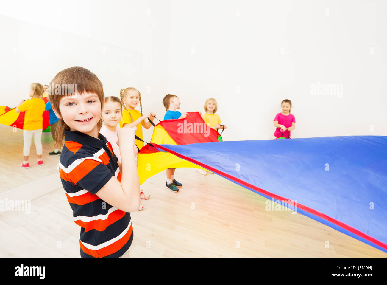 Smiling boy playing parachute with friends in gym Stock Photo Alamy
