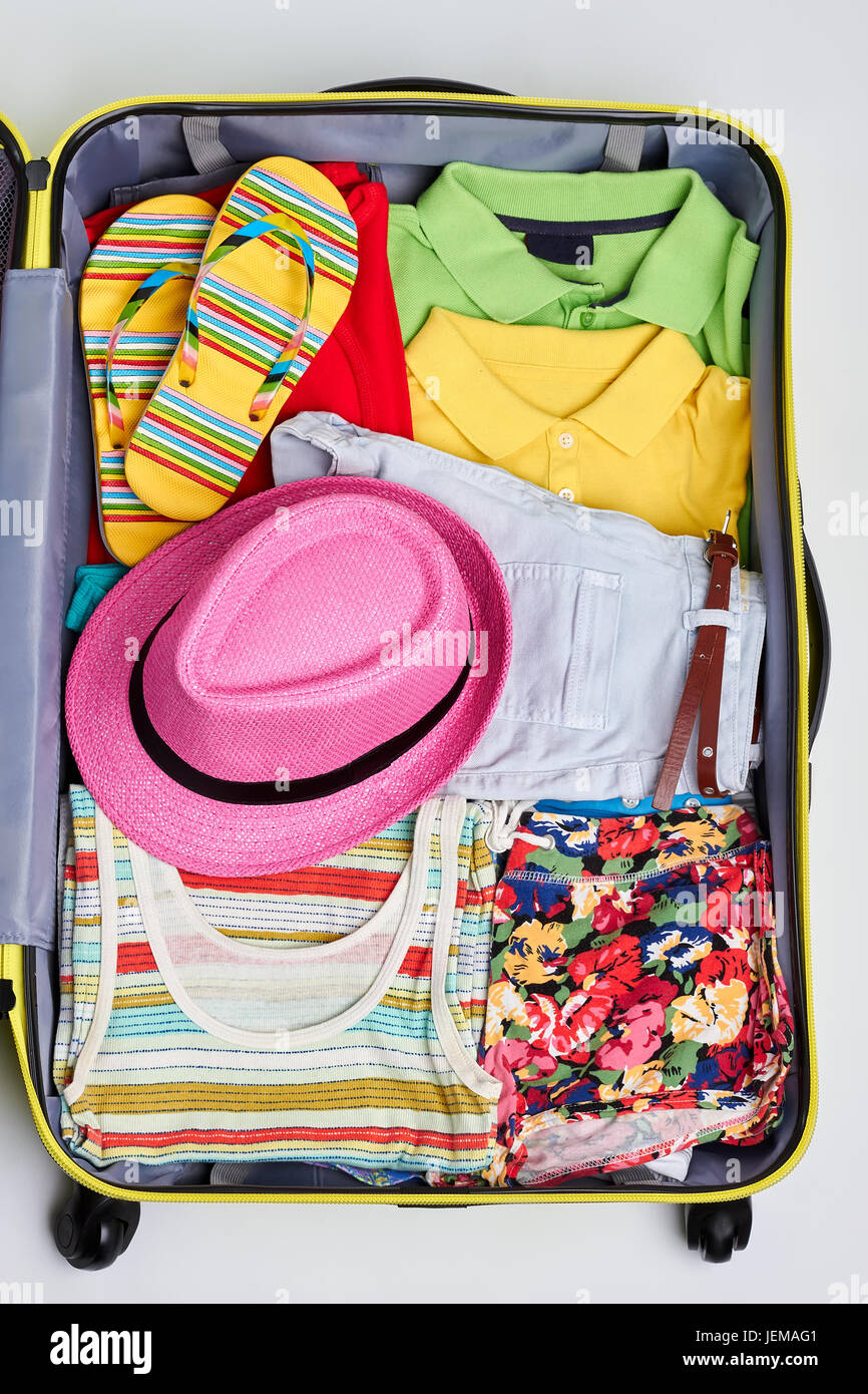 Colorful woman clothes in suitcase. Bright summer stuff in opened traveler bag. Stock Photo