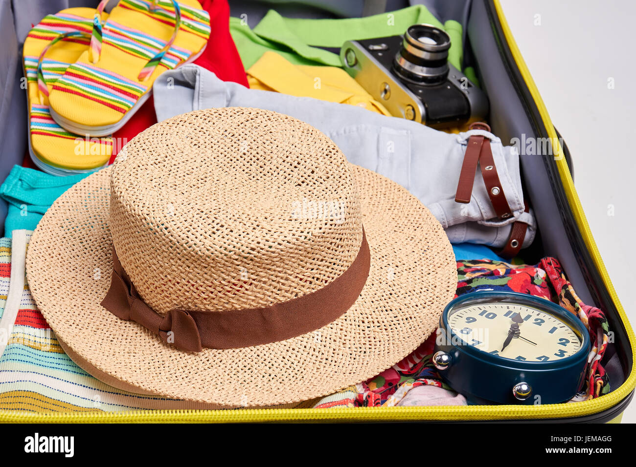 Woven hat, clothes in suitcase. Personal accessories for summer voyage. Stock Photo