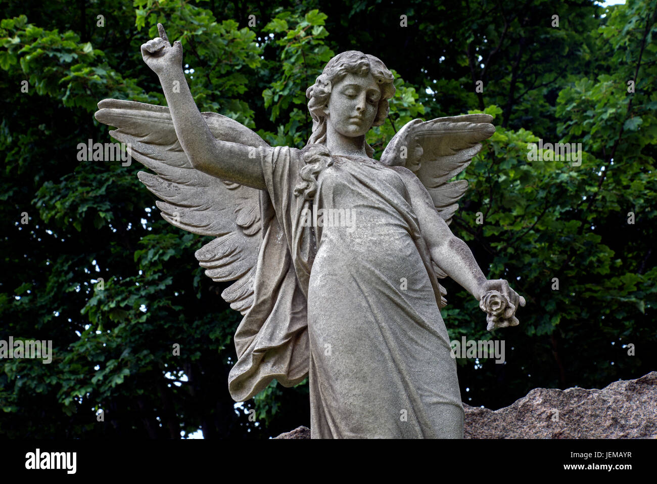Statue of an angel holding a flower and pointing to the heavens in Grange Cemetery, Edinburgh. Stock Photo