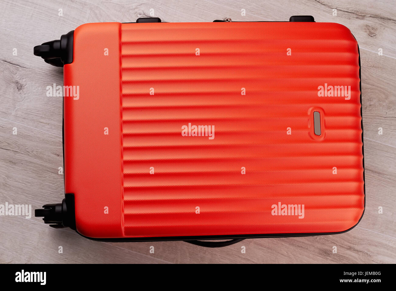 Red traveler suitcase close up. Modern wheeled luggage for travelling abroad. Stock Photo