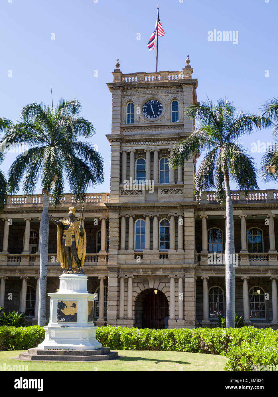 Kamehameha I statue in Honolulu: Clock tower of the old Judiciary Building is enscribed in Hawaiian: Ua Mau Ke Ea O Ka Aina I Ka Pono. An american flag and the state flag of Hawaii flies above. The building is a favourite location shot for the TV show Hawaii Five-O. Stock Photo