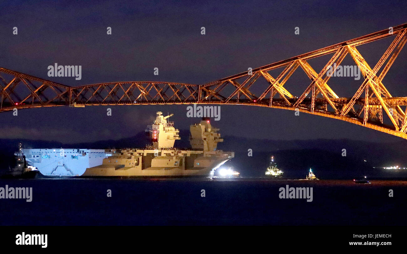 HMS Queen Elizabeth, one of two new aircraft carriers for the Royal Navy, is pulled by tugs under the Forth Rail Bridge in the Firth of Forth, as she sets sail to begin her sea trials. Stock Photo