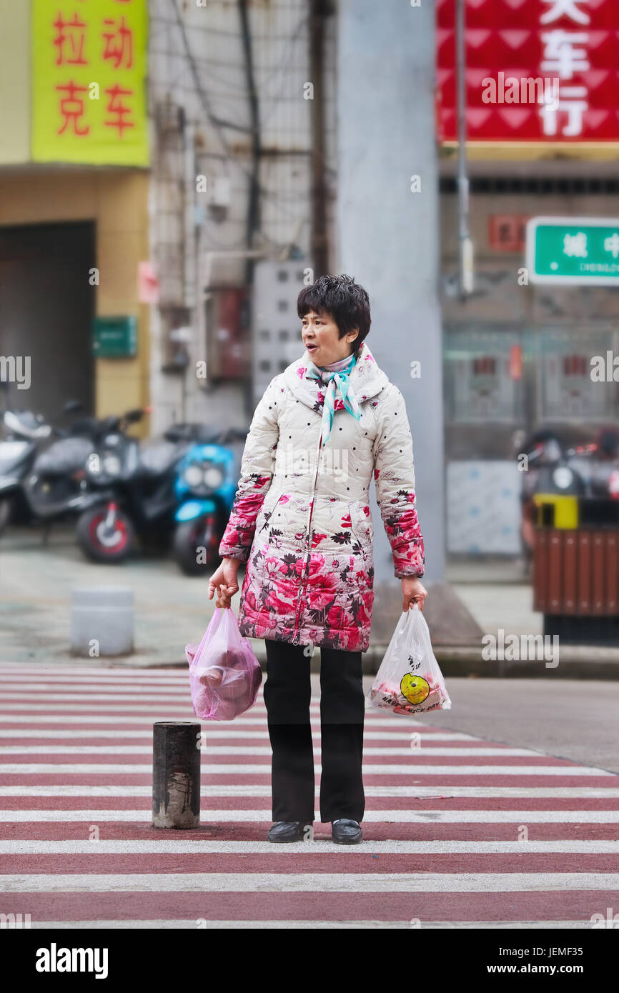 Woman on zebra with groceries. Economic disparity between urban China and rural areas is among the world’s largest, forms economic-cultural-social gap Stock Photo