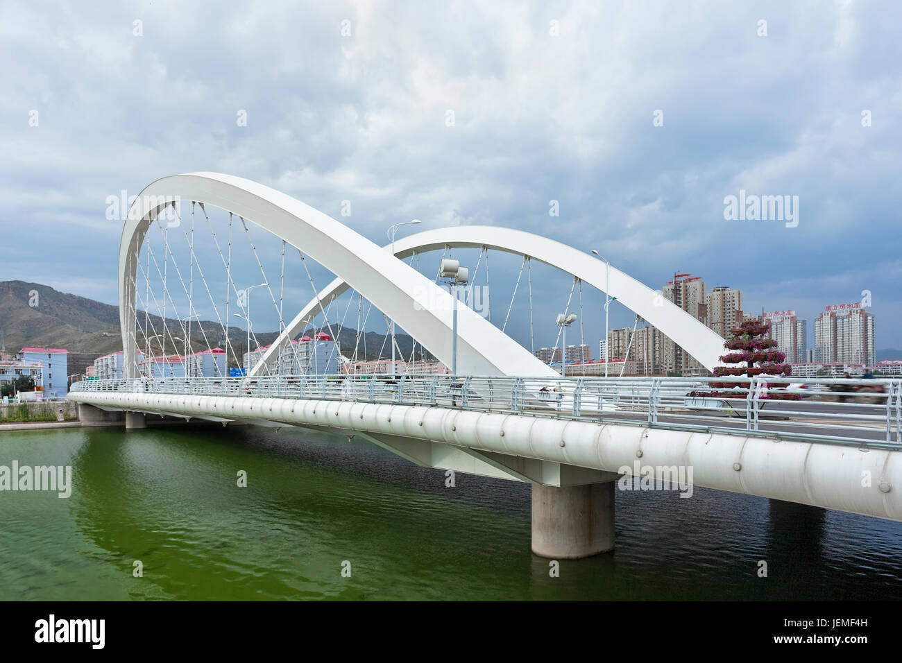 White modern bridge crossing a green canal in Zhangjiakou, Hebei Province, China. Stock Photo