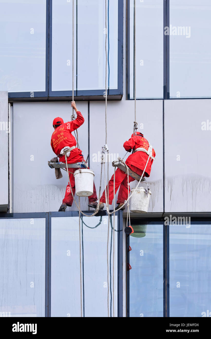 BEIJING - APRIL 28, 2009. Window cleaners at work. They are known as spider-men because they entrust their lives to a single thread, made of hemp. Stock Photo