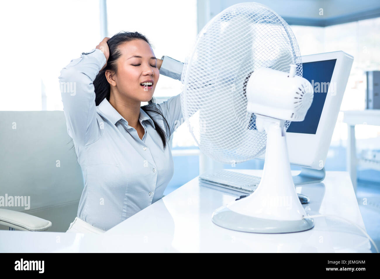 Businesswoman sitting in front of fan Stock Photo - Alamy