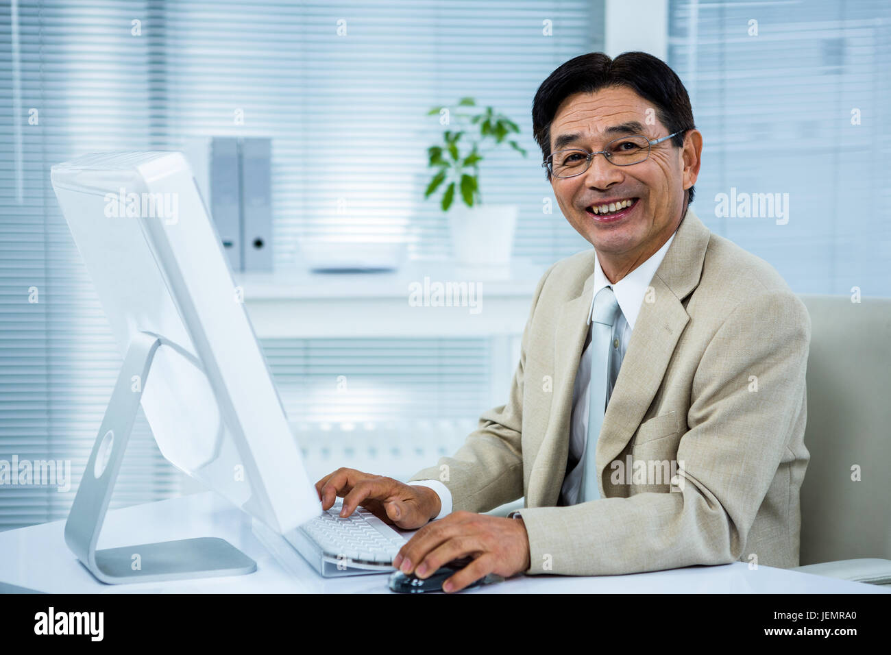 Smiling businessman using his computer Stock Photo - Alamy