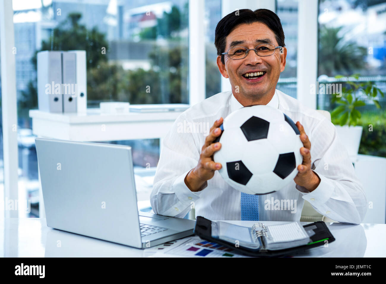 Asian businessman holding soccer ball Stock Photo - Alamy
