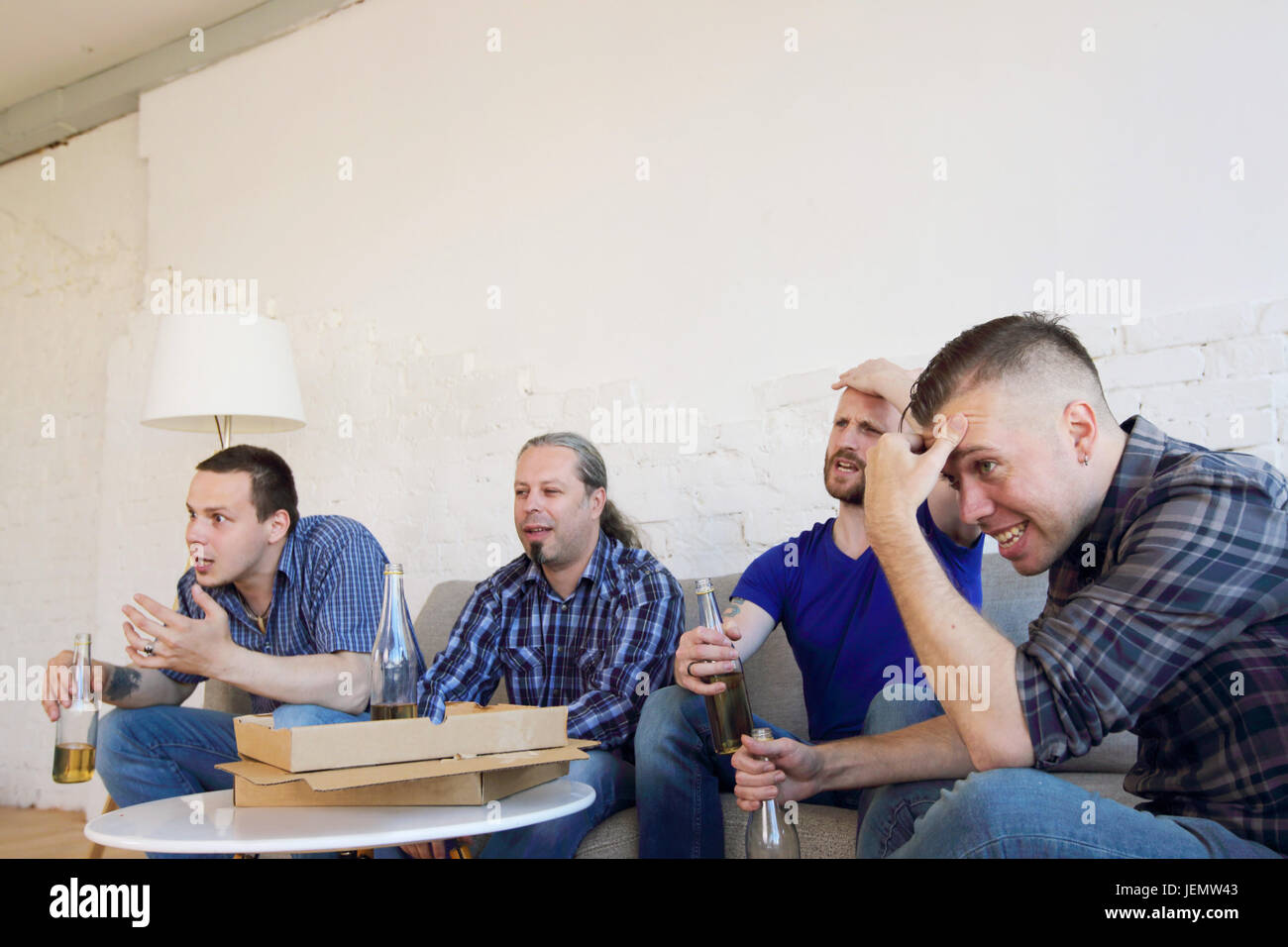 Male friends sports fans watching loosing football match on TV at home