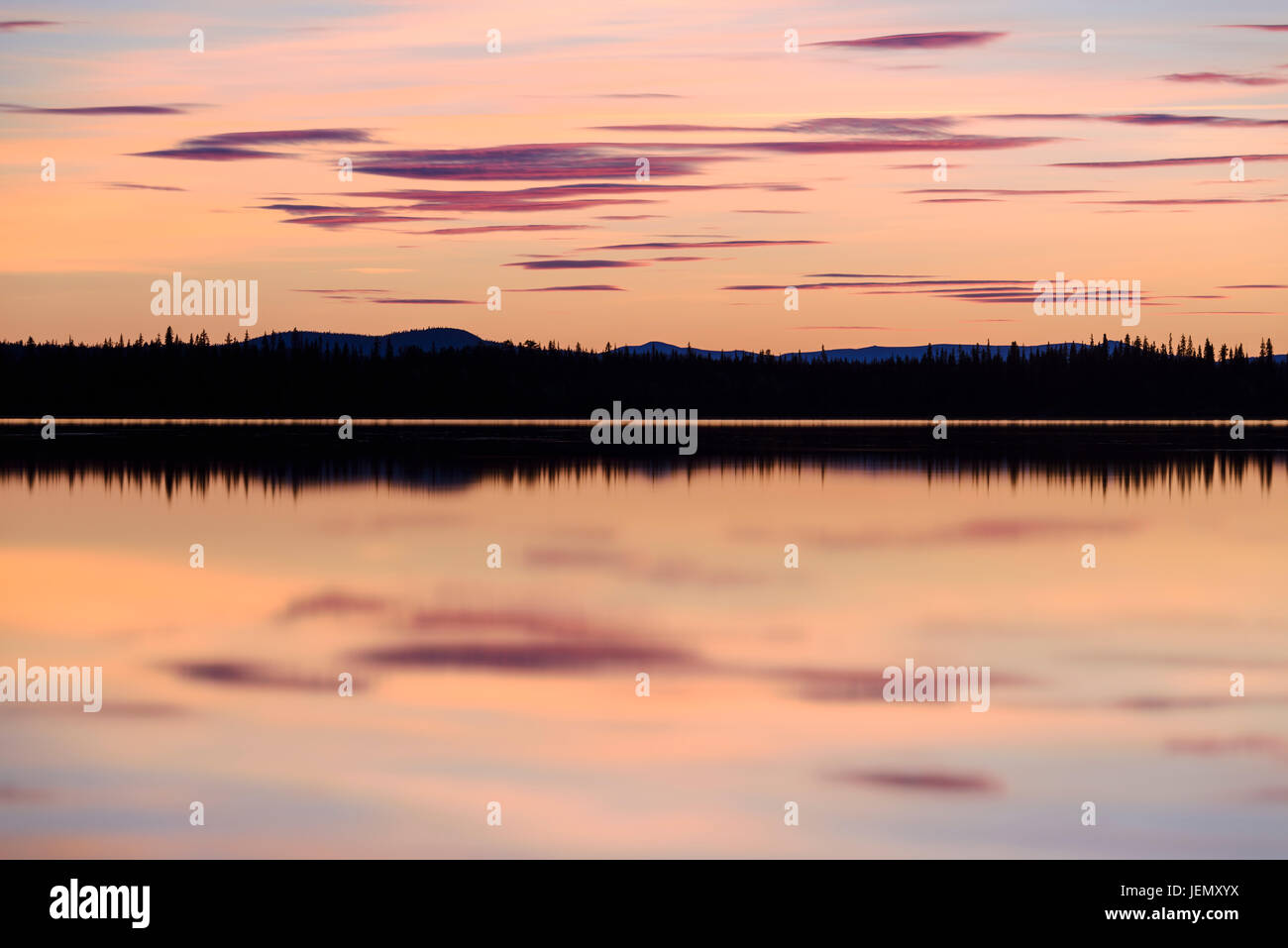 Forest reflecting in lake at sunset Stock Photo - Alamy
