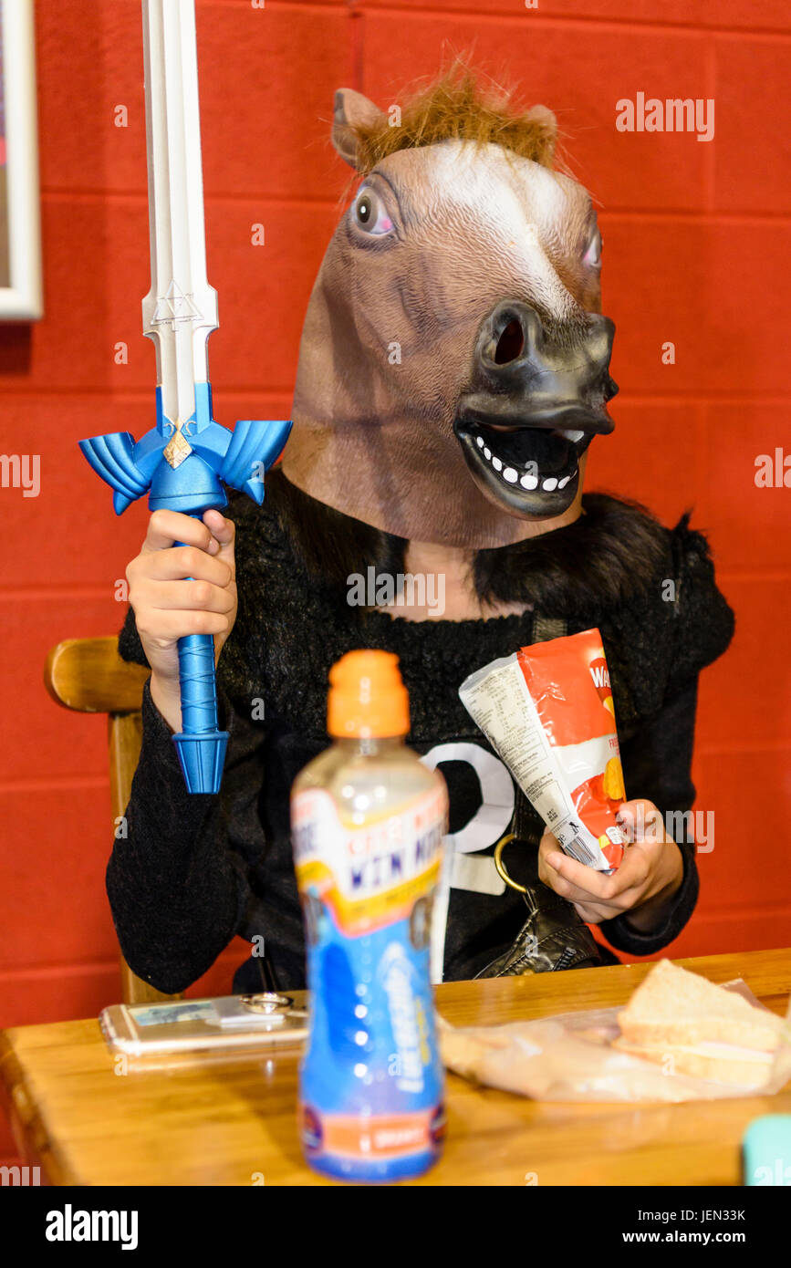 Lisburn, Northern Ireland.  25/06/2017 - A young lady dresses with a horses head and a sword, as she eats lunch at MCM Comicon Stock Photo