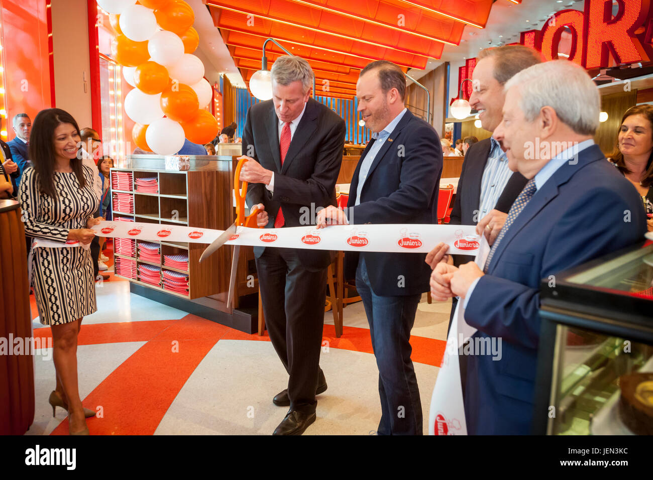 New York, USA. 26th June, 2017. New York Mayor Bill de Blasio, left, and Junior's co-owner Alan Rosen, right, cut the ribbon at the ceremonial opening of the second Times Square branch of Junior's Restaurant. in the former Ruby Foo's space, on Monday, June 26, 2017. The original Junior's is located in Downtown Brooklyn and is beloved for it's famous cheesecake. Junior's has opened a second space in Times Square in the now closed Ruby Foo's location. The new restaurant seats 300 people. ( © Richard B. Levine) Credit: Richard Levine/Alamy Live News Stock Photo