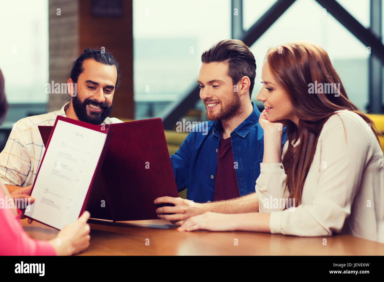 smiling friends discussing menu at restaurant Stock Photo - Alamy