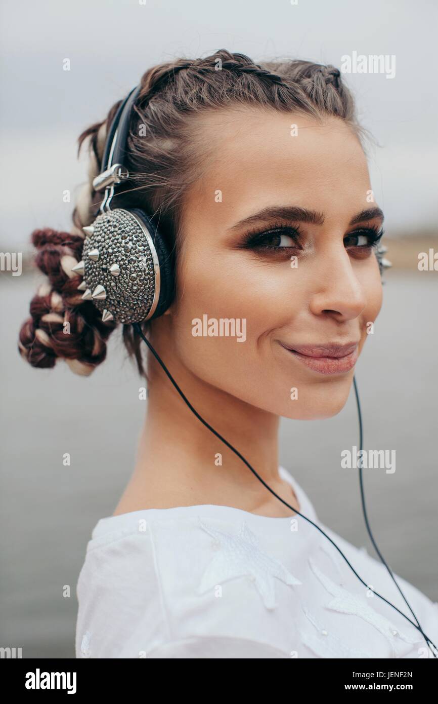 Portrait of a smiling woman wearing spiked headphones Stock Photo