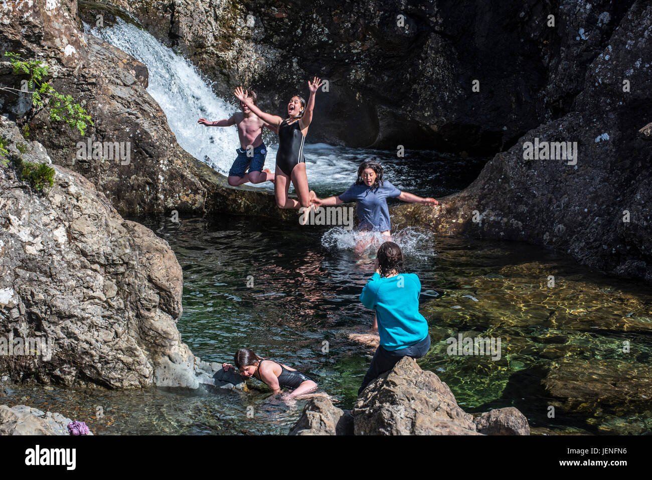 Happy children jumping in water of the Fairy Pools, succession of waterfalls in Glen Brittle on the Isle of Skye, Scottish Highlands, Scotland, UK Stock Photo