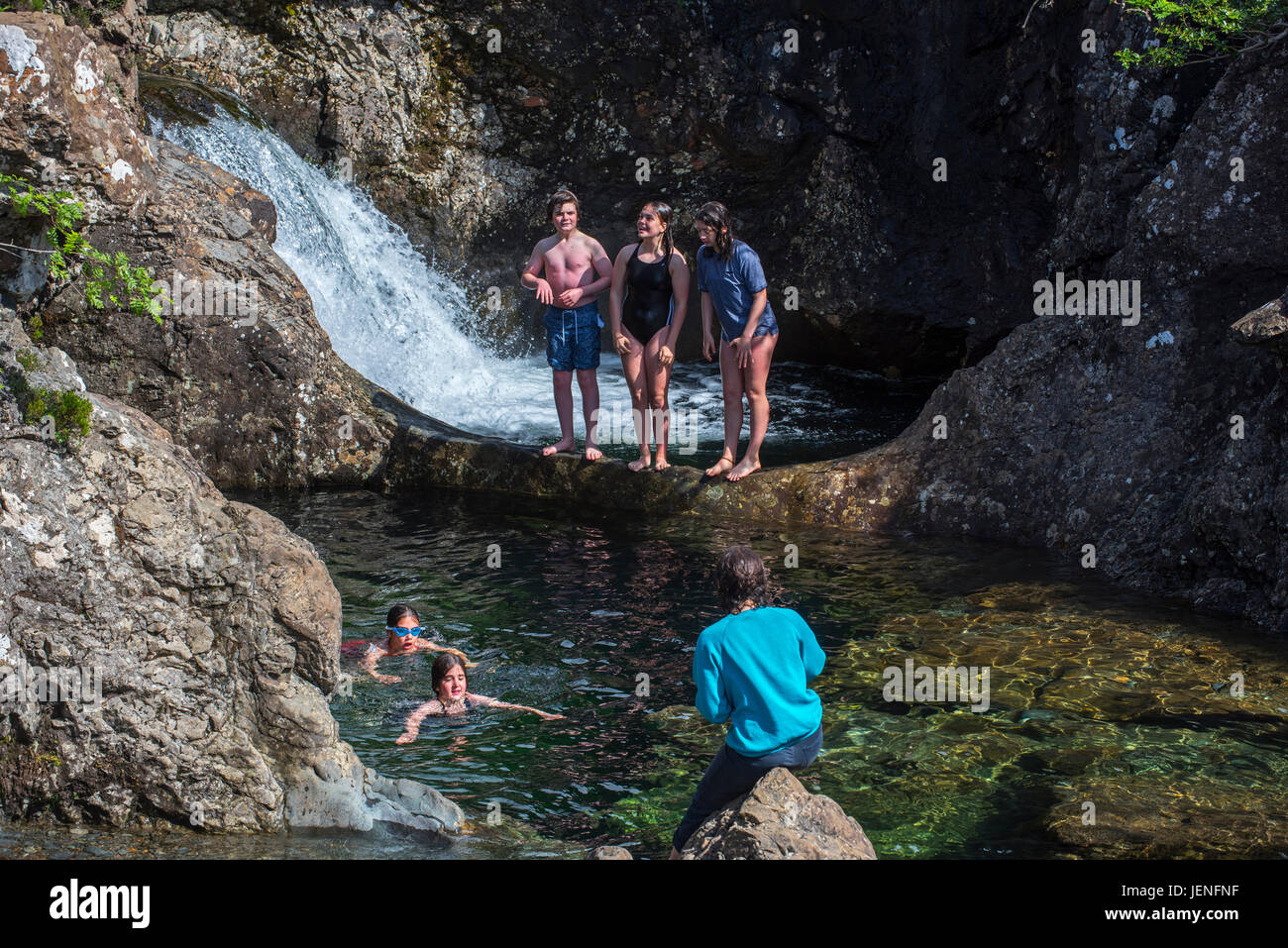 Happy children swimming in water of the Fairy Pools, succession of waterfalls in Glen Brittle on the Isle of Skye, Scottish Highlands, Scotland, UK Stock Photo