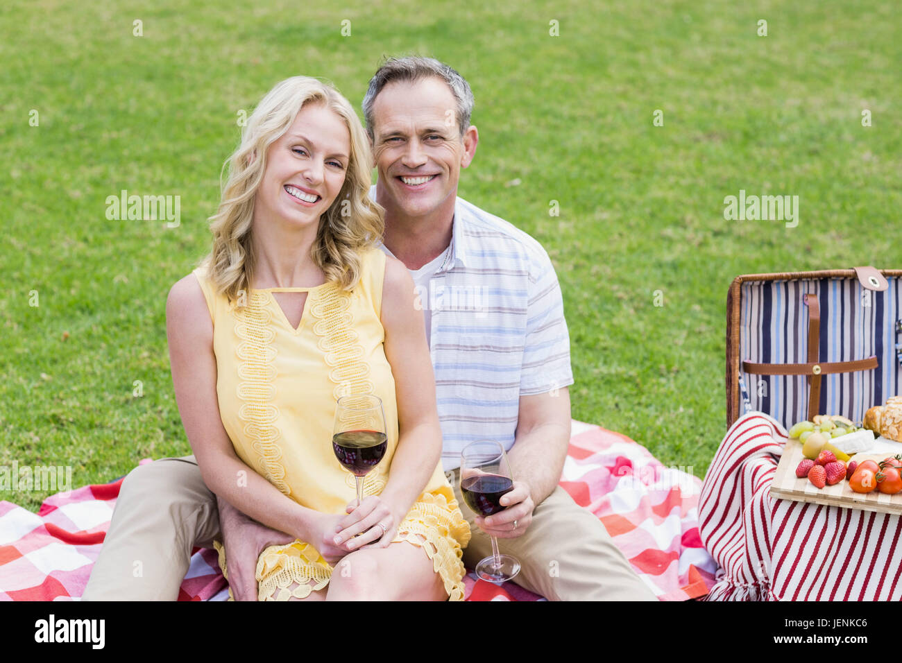 Happy couple having a picnic with wine Stock Photo - Alamy