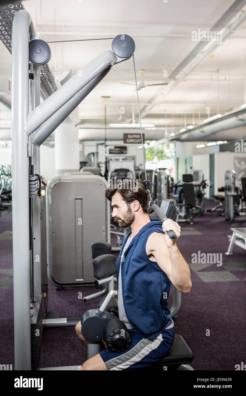 Focused man using weights machine for arms Stock Photo