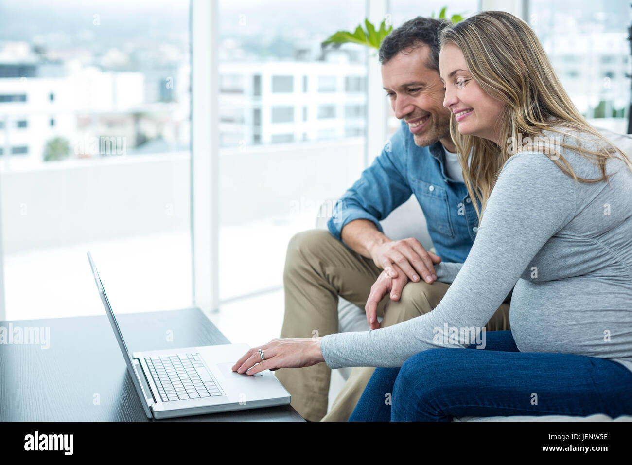 Couple using laptop in living room Stock Photo - Alamy