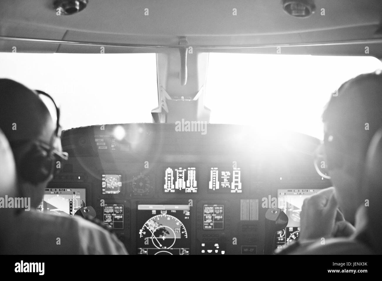 Rear view of two pilots sitting in cockpit of airplane Stock Photo