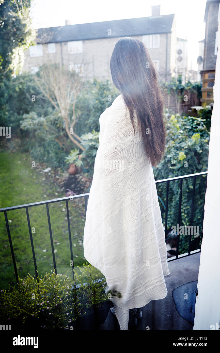 Woman wrapped in blanket standing on balcony Stock Photo - Alamy