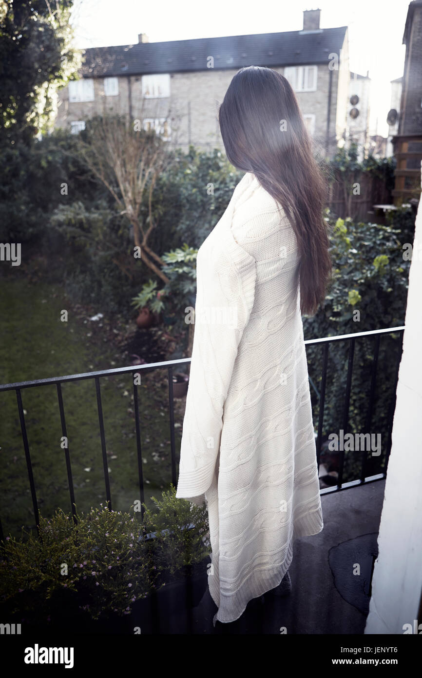 Woman wrapped in blanket standing on balcony Stock Photo - Alamy