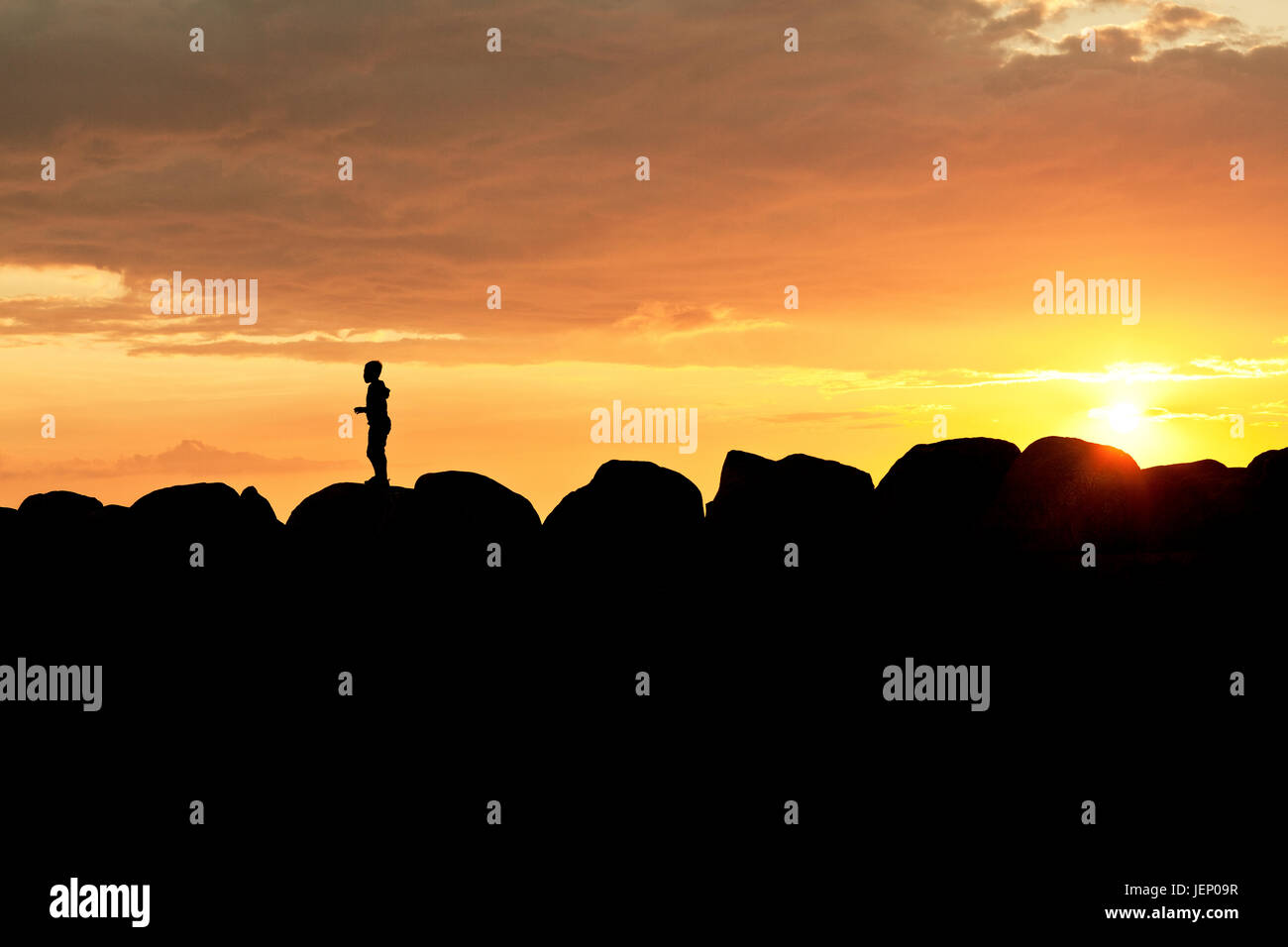 Silhouette of person standing on rocks at sunset Stock Photo - Alamy