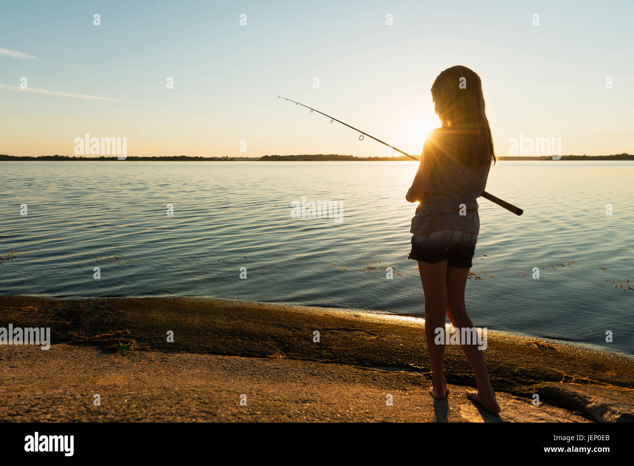 Girl fishing in sea, dusk Stock Photo - Alamy