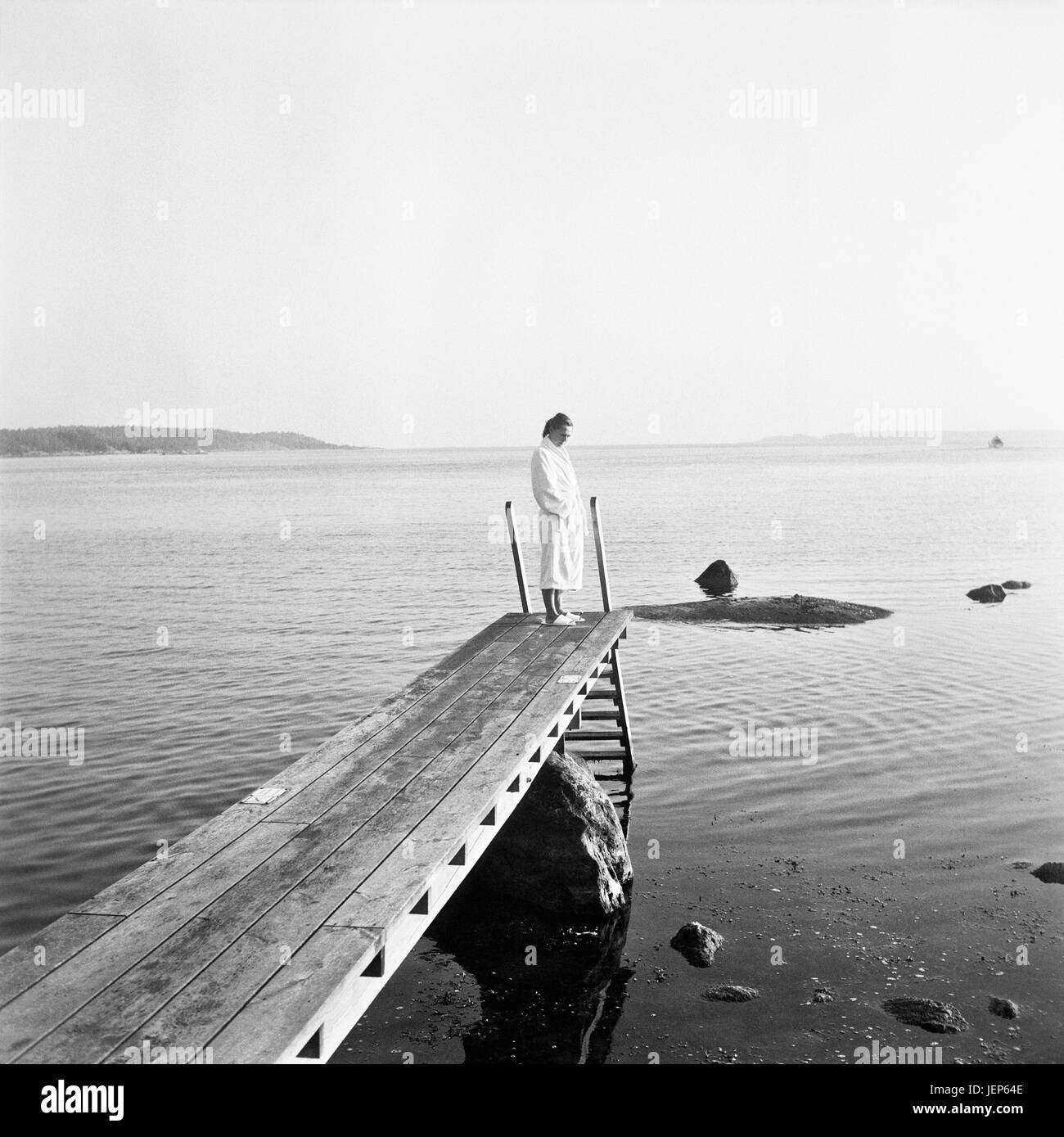 Woman in dressing gown standing at jetty Stock Photo
