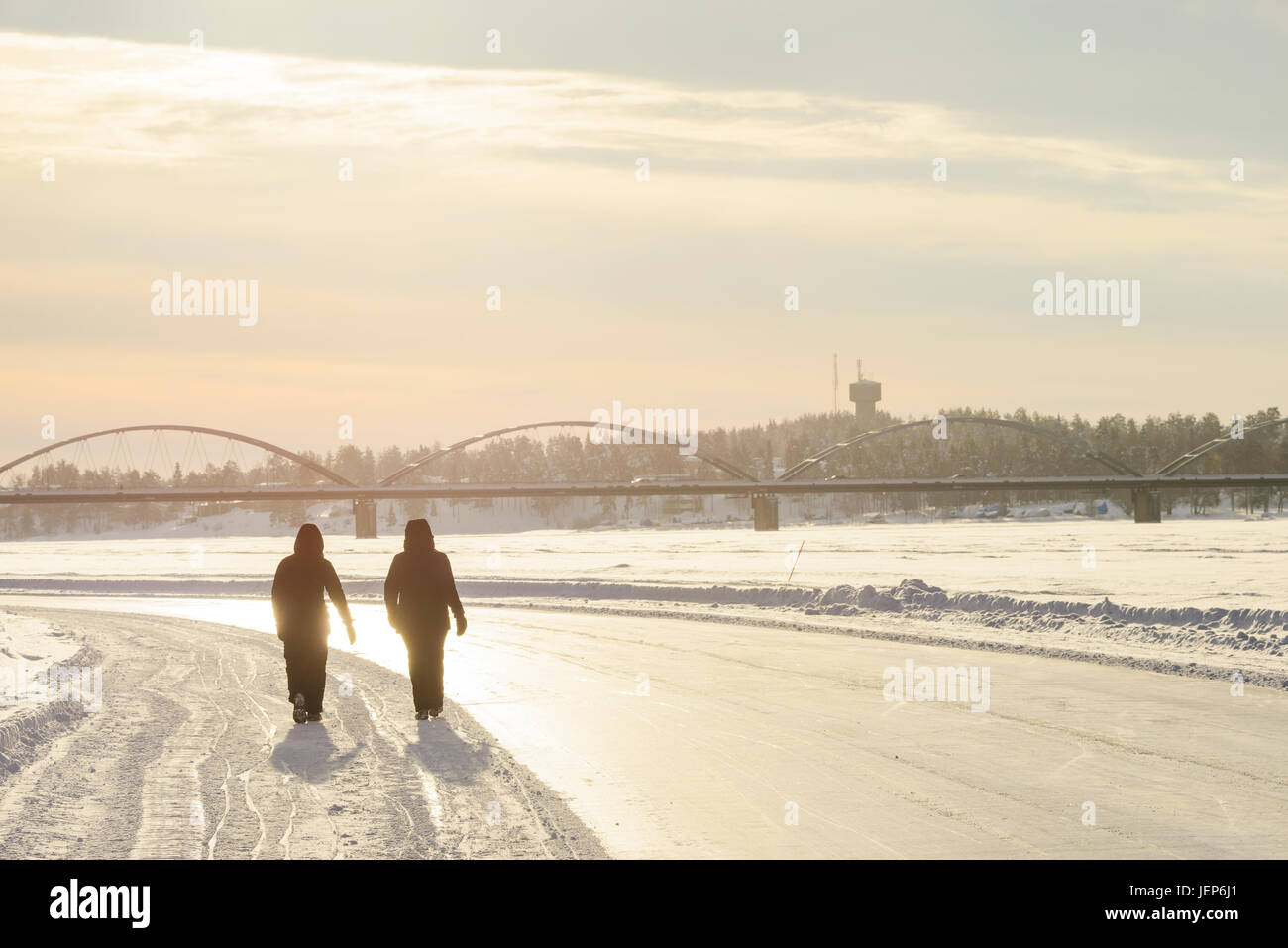 Silhouettes of people walking along frozen river Stock Photo