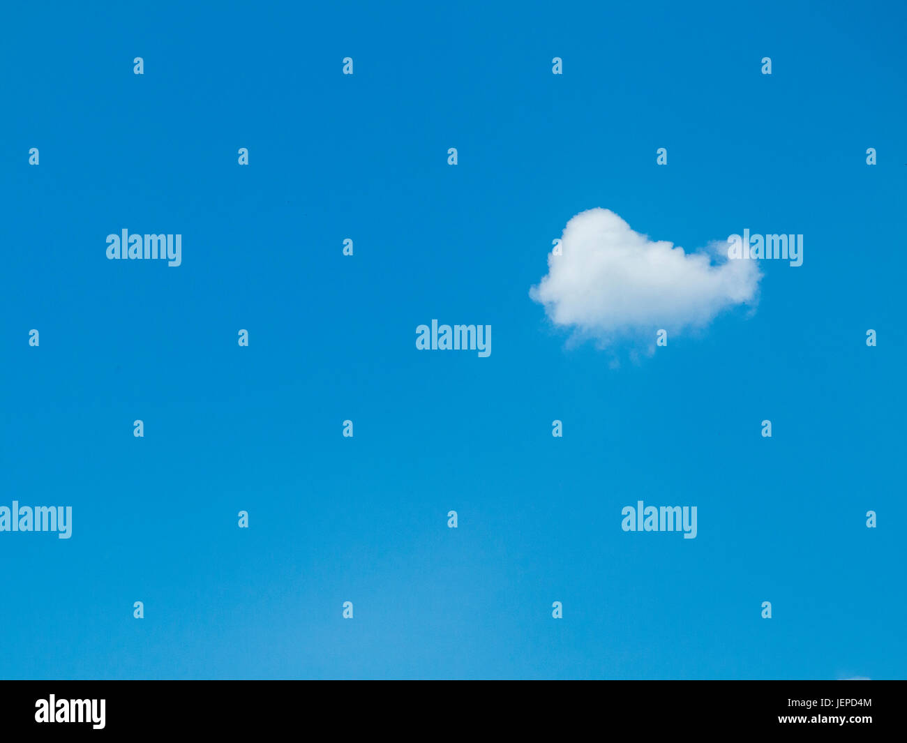 A single cloud on a sunny day with a bright blue sky with plenty of space for copy Stock Photo