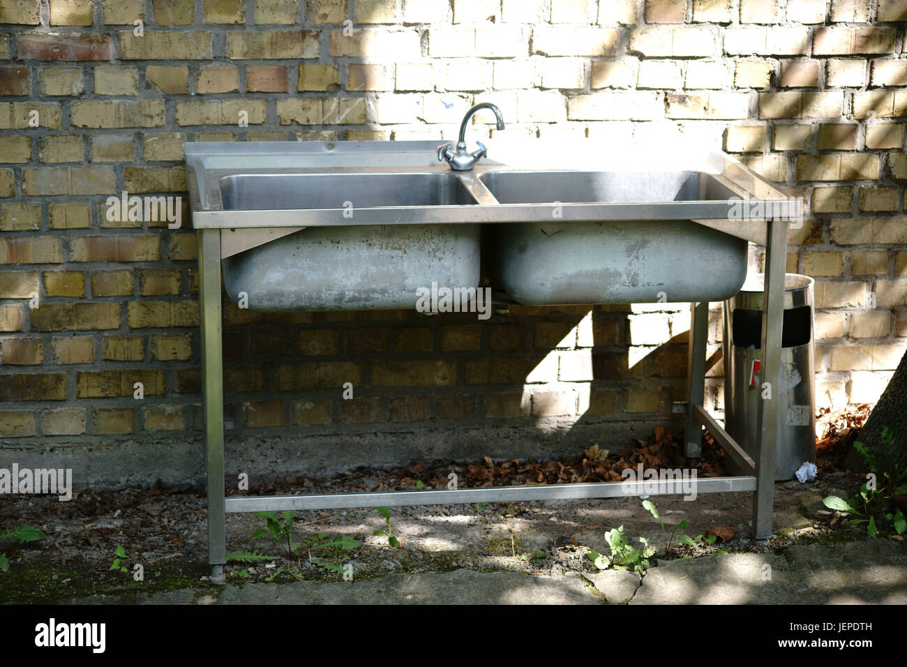 An old dishwashing basin on four legs stands outside on a house wall