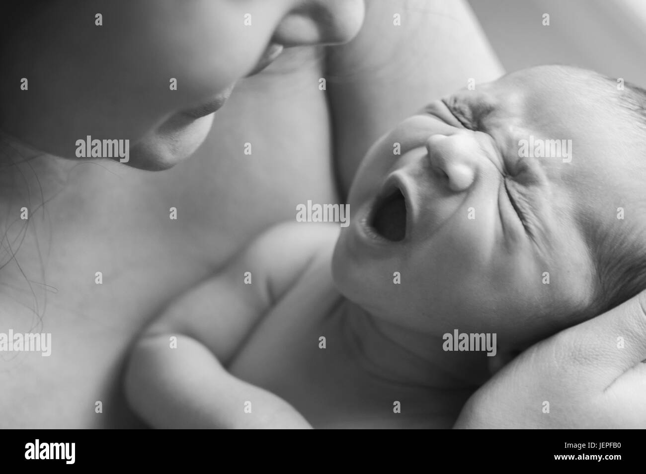 Model Released Photograph of a Baby yawning on his mothers lap Stock Photo