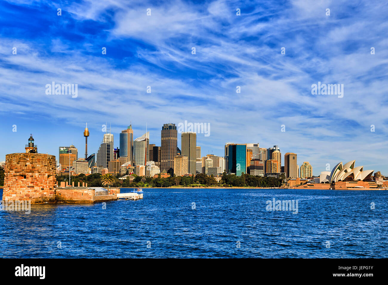 Skyline of Sydney city CBD from harbour with Fort Denison and wharf on a sunny warm day. Stock Photo