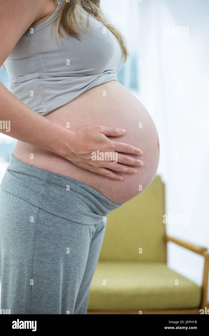Pregnant woman holding her stomach Stock Photo - Alamy