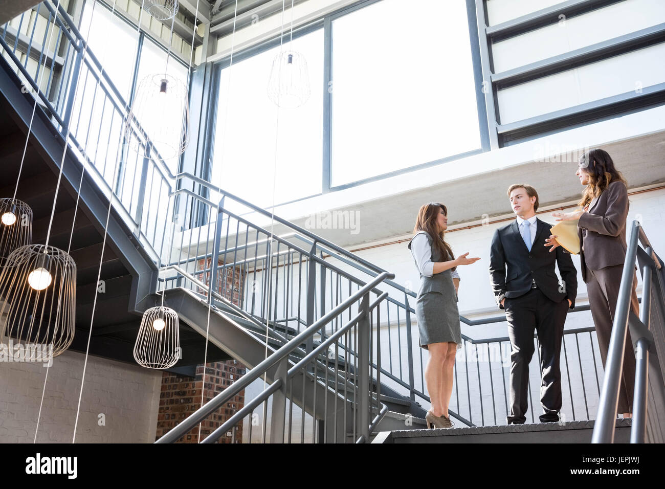 Three executives standing on a staircase Stock Photo - Alamy