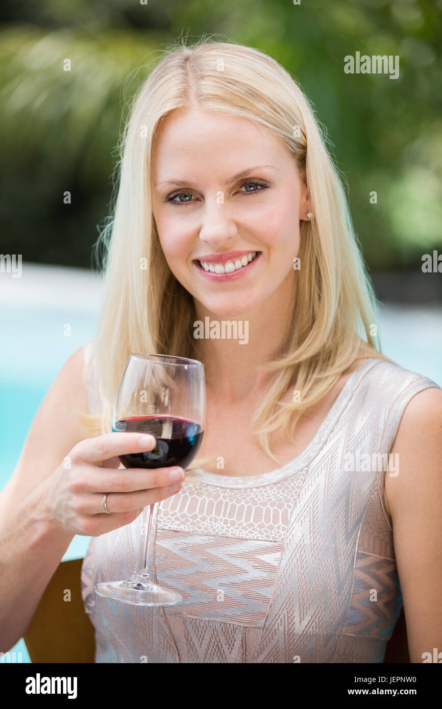 Smiling young woman holding red wine glass Stock Photo - Alamy