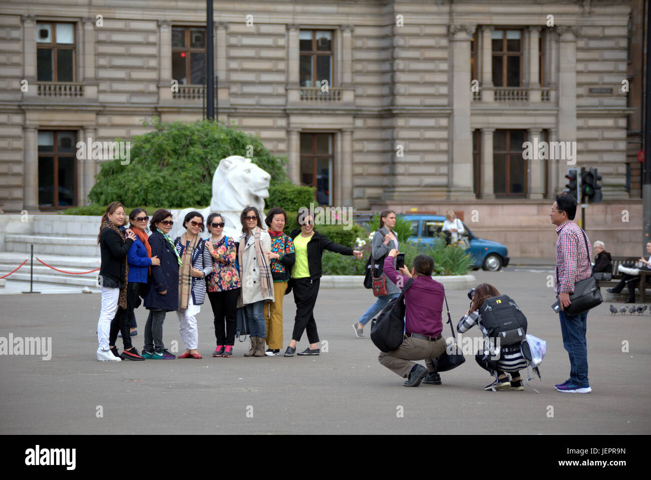 Asian tourists in George Square Glasgow Scotland taking selfies and photographs mainly Chinese and Japanese people Stock Photo