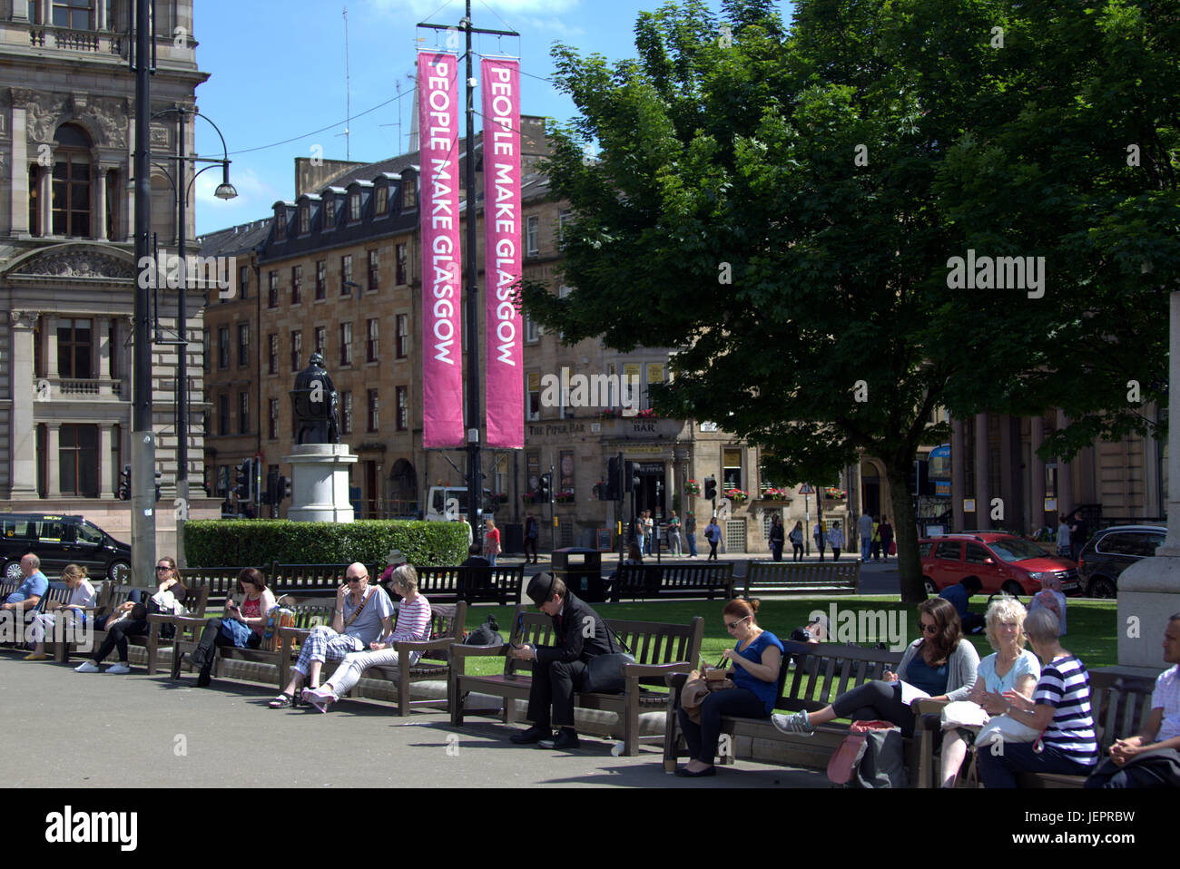 Summer weather returns and people enjoy the summer on the streets , George Square , Scotland   tourists catches some of the sunny weather Stock Photo