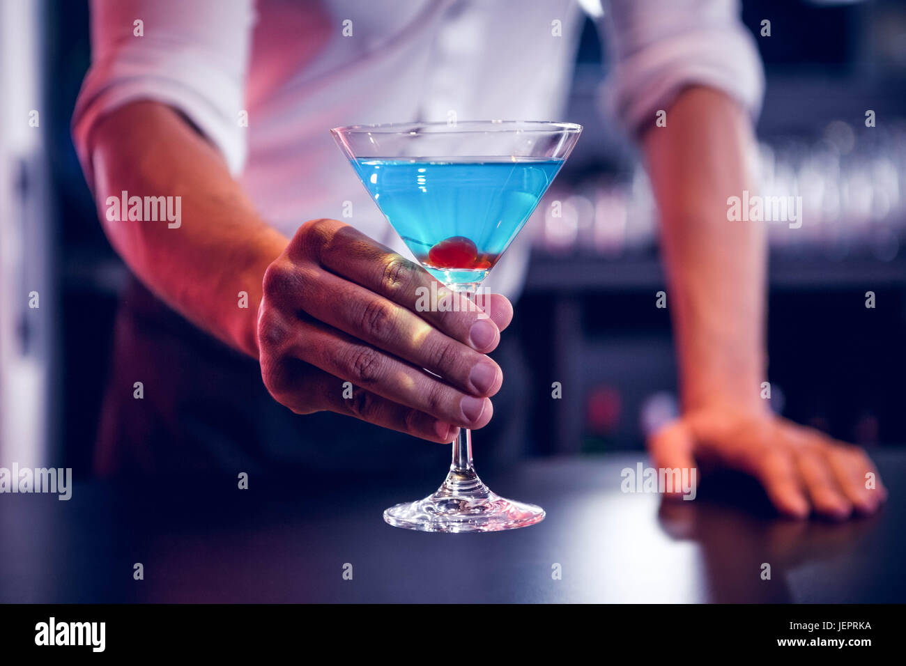 Bartender serving a blue martini Stock Photo Alamy