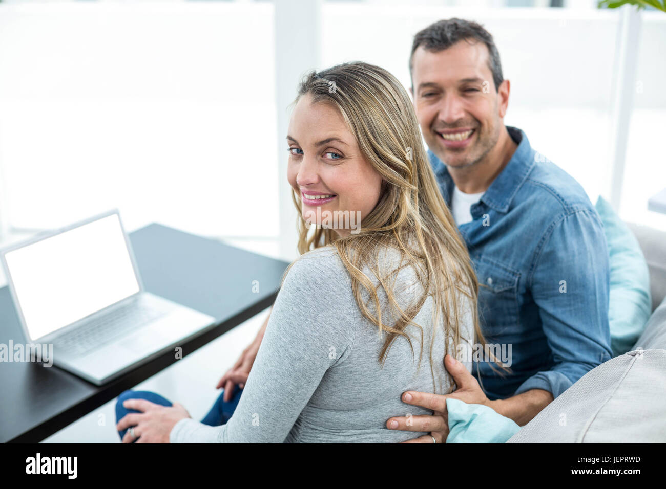 Couple using laptop in living room Stock Photo - Alamy